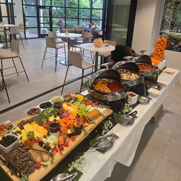 A long buffet table with a charcuterie board, chafing dishes, and a modern dining area.